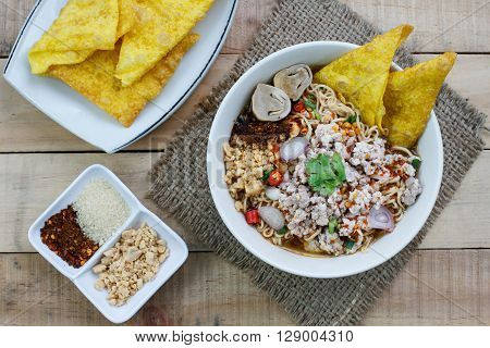 Spicy instant noodle soup with minced pork on wood background Top view