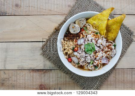 Spicy instant noodle soup with minced pork on wood background Top view