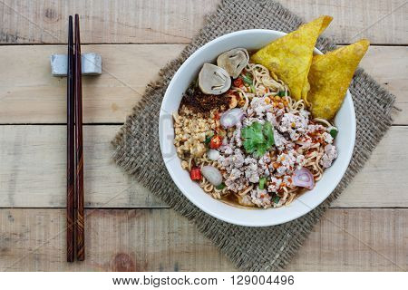 Spicy instant noodle soup with minced pork on wood background Top view
