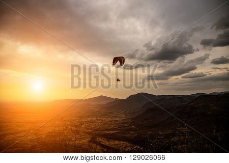 Silhouette Of Sky Diver Flies On Background Of Sunset Sky