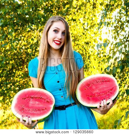 Smilingl young blonde woman holding two halfs of juicy watermelon
