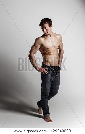 Muscular Male Model Bodybuilder With Unbuttoned Jeans. Studio Shot On Gray Background. Fitness Model
