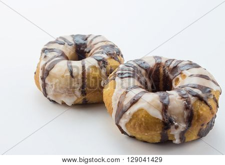 Two striped chocolate and white icing dribbled dougnuts close up isolated on white