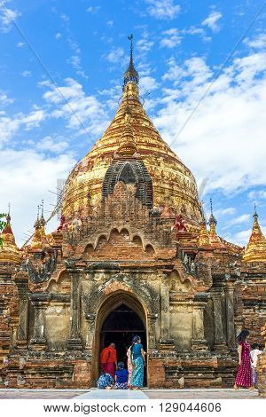 Bagan Myanmar - January 12 2012: Local people near the golden pagoda in the plain with thousand of 880-year old temple ruins.
