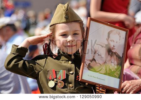 Orel Russia - May 9 2016: Celebration of 71th anniversary of the Victory Day (WWII). Girl in military uniform with medals carrying soldier's portrait closeup