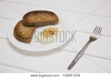 poached egg with two toasts on rustic background