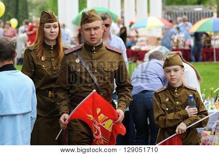 Orel Russia - May 9 2016: Celebration of 71th anniversary of the Victory Day (WWII). Family in soviet military uniform with red flags closeup