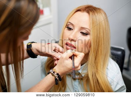 Close up of a make-up artist contouring lips to model.