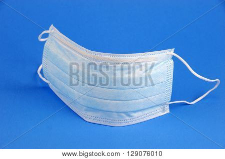 single medical ear-loop mask on blue background