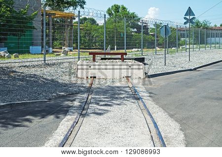 End of rail in an industrial area on against the background of a fence with barbed wire