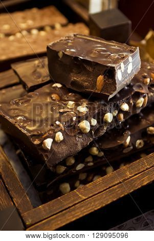 Pile of dark chocolate with whole hazelnuts on the table in shop