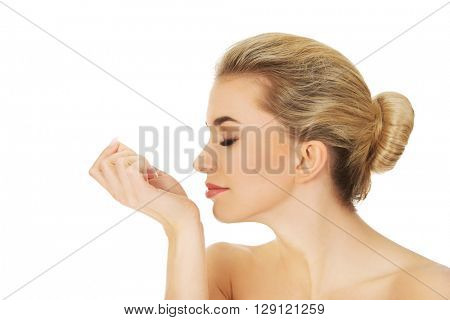 Young woman smelling perfume on her wrist.