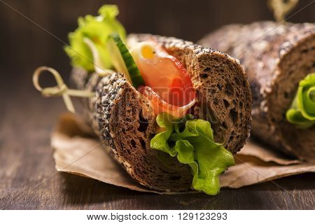 Tasty rye bread sandwhiches with ham, cheese and vegetables over dark wooden table