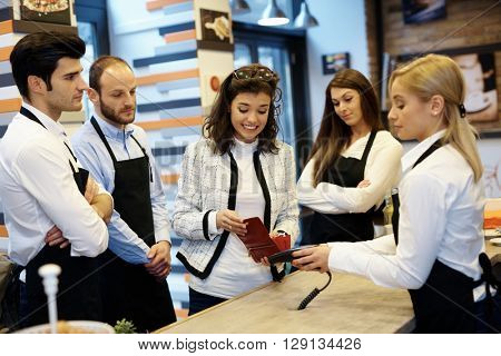 Elegant young woman unable to pay bill in cafe, feeling embarrassed.