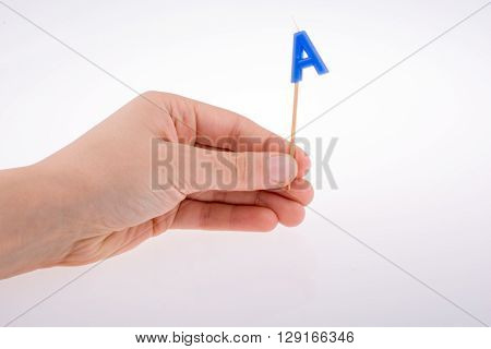 Color candle in hand on sticks writes the letterA