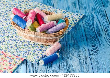 Wooden table with colored sewing utensils in backet