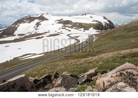 Snow drapes the mountain slopes along the Beartooth Highway which loops into a hairpin curve Wyoming USA