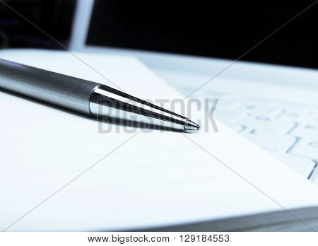 Pen, paper and white laptop. Business concepts.
