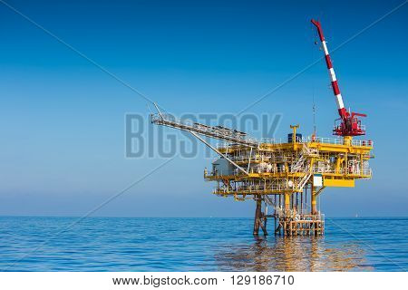 Oil and Gas wellhead remote platform crane lifting cargo for loading to supply boat.