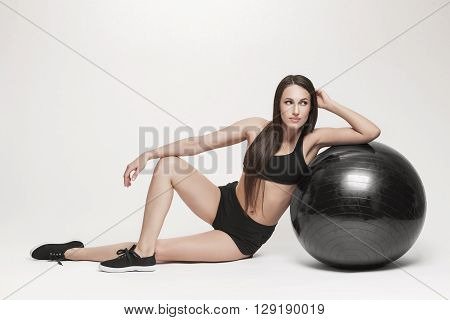 Portrait of young attractive woman doing exercises. Brunette with fit body exercising with fitness ball. Series of exercise poses.