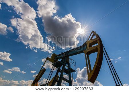 Oil and gas well profiled on blue sky with cumulus clouds