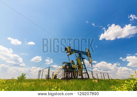 Oil and gas well profiled on blue sky with cumulus clouds