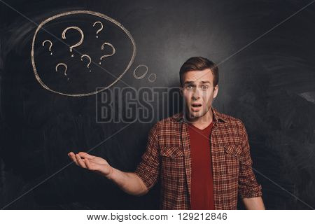 Attractive Young Freelancer At A Loss On The Background Of Chalkboard