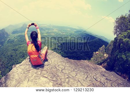 young woman hiker use smartphone taking photo on seaside mountain top