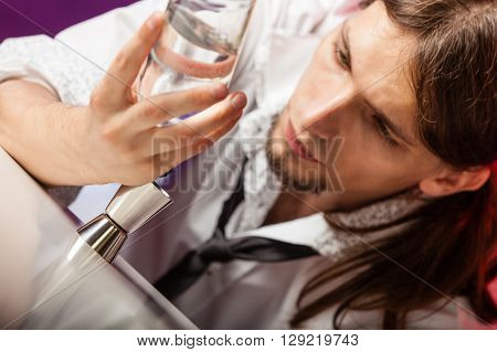 Drink alcohol liquor drink relax concept. Closeup of barman at work. Male bartender looks at glass and bottle.