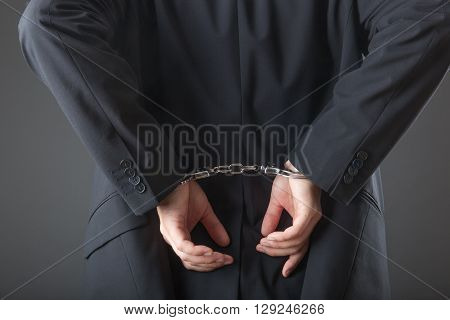 businessman in handcuffs arrested isolated on grey background