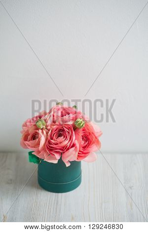 bunch of pale pink ranunculus persian buttercup  light background, wooden surface. glass vase.  green box  spring, summer