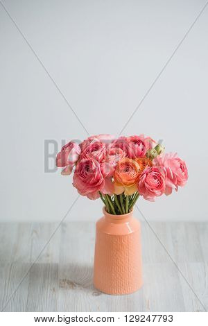 bunch of pale pink ranunculus persian buttercup light background, wooden surface. glass vase.  spring, summer