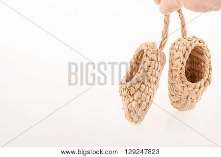 Pair of footware made of straw on white background
