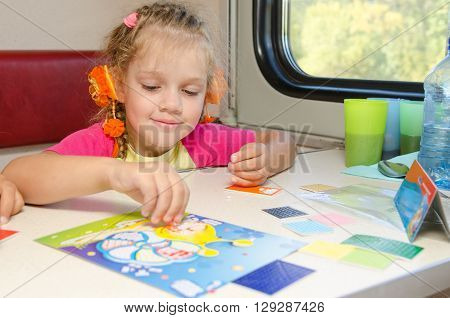 A Small Child In A Train Of Fun Playing At The Table At The Lower Place In The Second-class Compartm