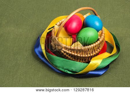 Easter Wicker basket with pink vines painted chicken eggs on a background of green fabric from flax.