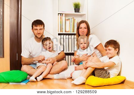 Big happy Caucasian family, mother, father and three age-diverse sons, sitting on the floor at home