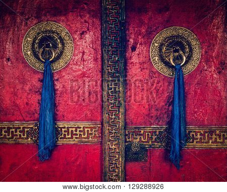 Vintage retro effect filtered hipster style image of gate of Spituk Gompa (Tibetan Buddhist monastery) with ornamented decorated door handles. Ladakh, India