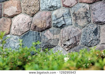 grey stone wall and green grass with shallow depth of field on the foreground