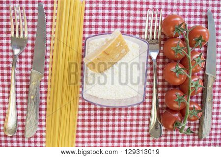 flat lay of pasta at tomato with raw spaghett icherry tomatoes and parmesan between cutleries