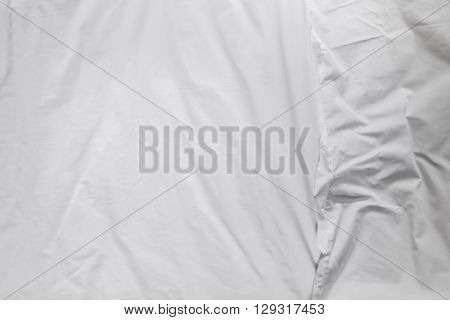 Top view of white bed sheets and pillow crease