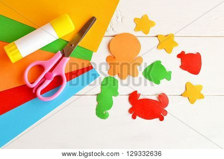 Sheets of colored paper, scissors, glue, paper fish and sea creatures. DIY concept. Kids craft idea