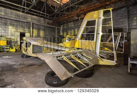Abandoned aviation factory of small aircraft . The partially-built airplane in a dark industrial building at night. Focus on the tail of plane