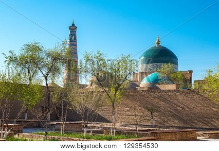 Uzbekistan Khiva a garden in city center with the Islam Kodija minaret and Mahmud mausoleum in the background