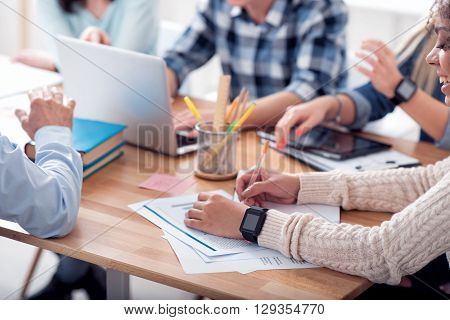 Working place. Concerned people sitting in the circle at the table expressing gladness while being fully involved in work