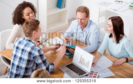 Together is better. Cheerful and content young people sitting at the table while studying and discussing something