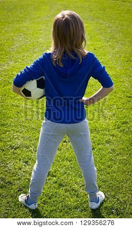 Nice smiling happy 8 years old boy stand with volleyball ball in the park field outside on sunny summer day