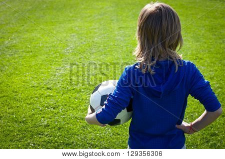 Nice smiling happy 8 years old boy stand with volleyball ball in the park field outside on sunny summer day