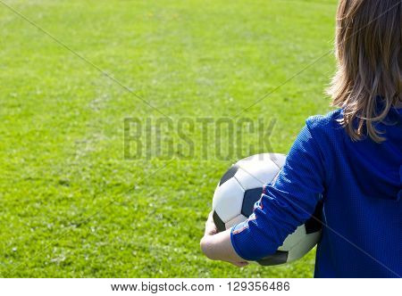 Nice smiling happy 8 years old boy stand with volleyball ball in the park field outside on sunny summer day