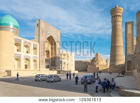 Buckara Uzbekistan - Aprilr 16 2014: Local people in the square with the Mir-i-Arab madrassah and the Kalon mosque in the background