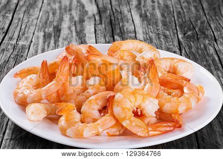 boiled tails of king shrimps on a white platter on an old rustic table close-up studio lights